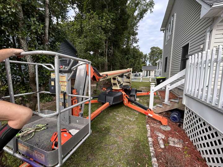 Compact orange tracked lift set up in a narrow side yard beside a house in Myrtle Beach, SC