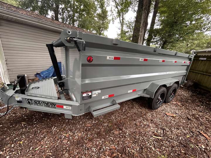 Grey dump trailer parked beside a house, ready to be loaded with brush in Myrtle Beach, SC