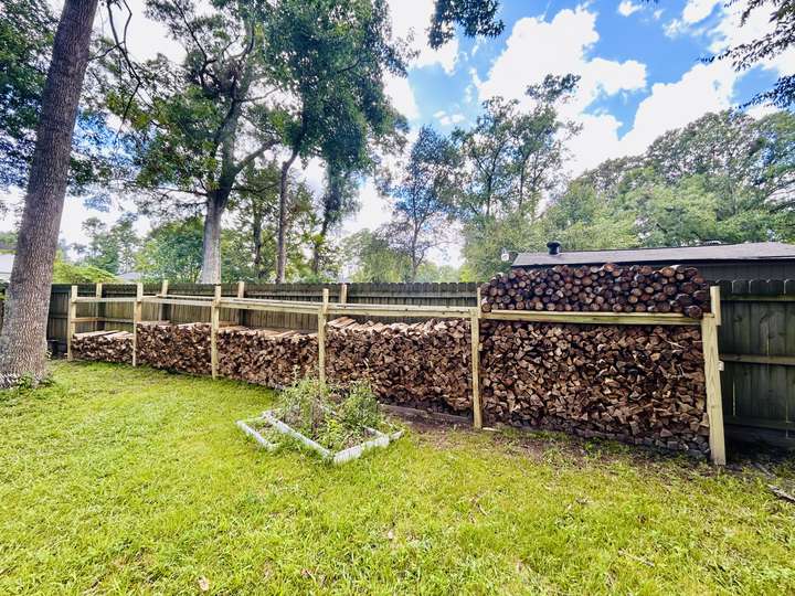 Long firewood racks along a backyard fence, fully stacked in Myrtle Beach, SC