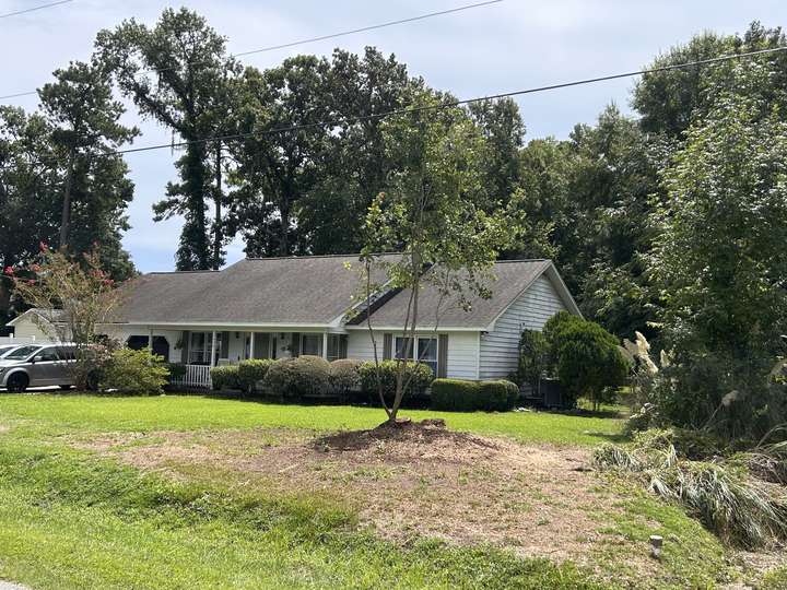 Front lawn of a brick house after a tree removal, with only the bare stump area left in Myrtle Beach, SC