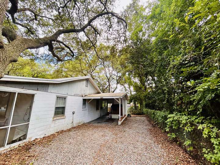 Live oaks arching over a white cottage and gravel driveway in Myrtle Beach, SC